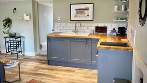 A modern kitchen with grey cabinets, a wooden countertop, and a tiled backsplash. - The Georgian Loft Apartment Central Bath (Bath)