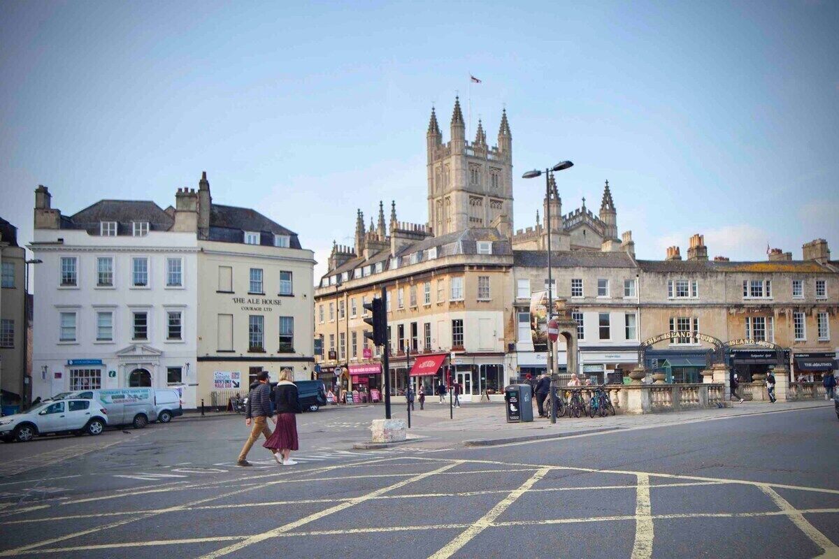 A street view with a prominent historical building featuring a tower and multiple windows.