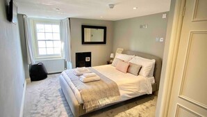 A bedroom with a large bed, a window, a mirror, and a radiator. - The Georgian Loft Apartment Central Bath (Bath)