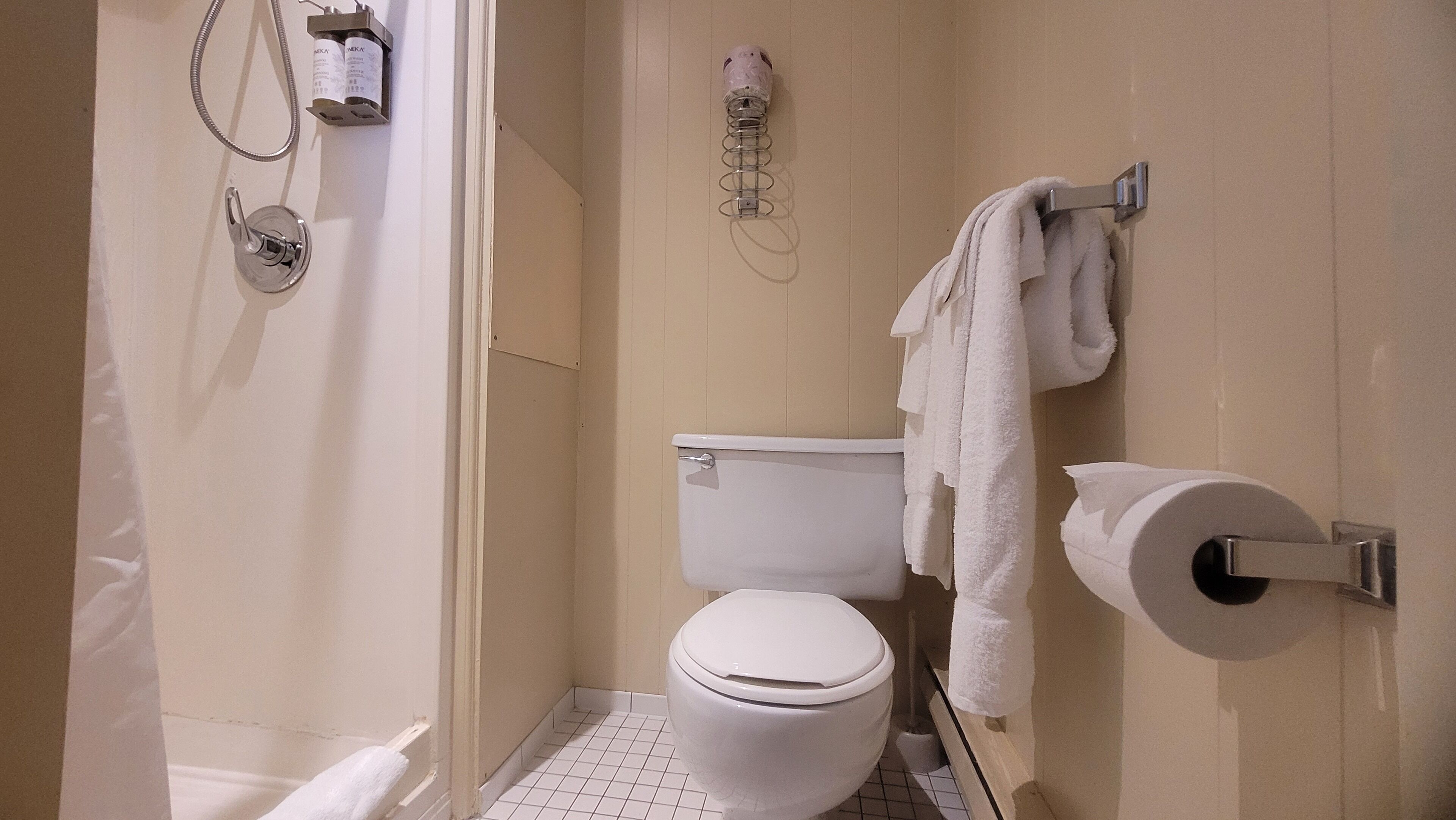 A small, clean bathroom with a toilet, a shower, and a towel rack.