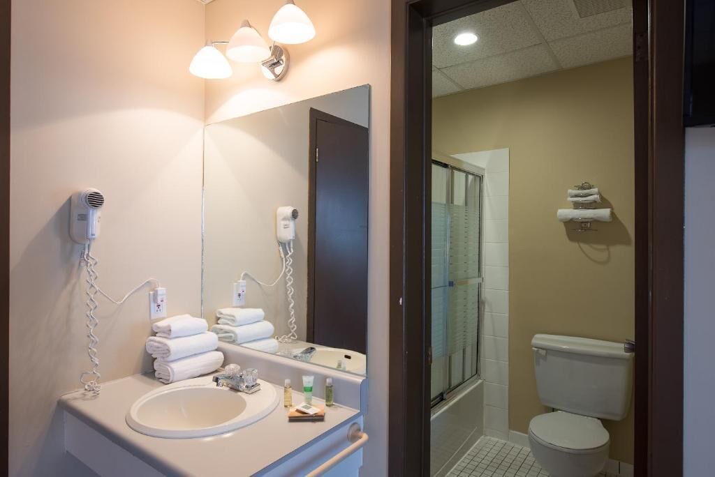 A bathroom with a sink, mirror, hairdryer, and towel rack.