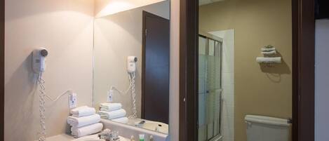 A bathroom with a sink, mirror, hairdryer, and towel rack.