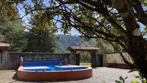 Una piscina circular con una combinación de colores azul y rojo, rodeada por un muro de piedra y un suelo de baldosas.