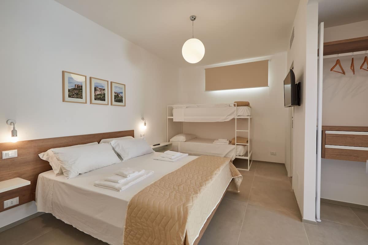 A hotel room with a large bed, a smaller bed, a TV, and a wardrobe.