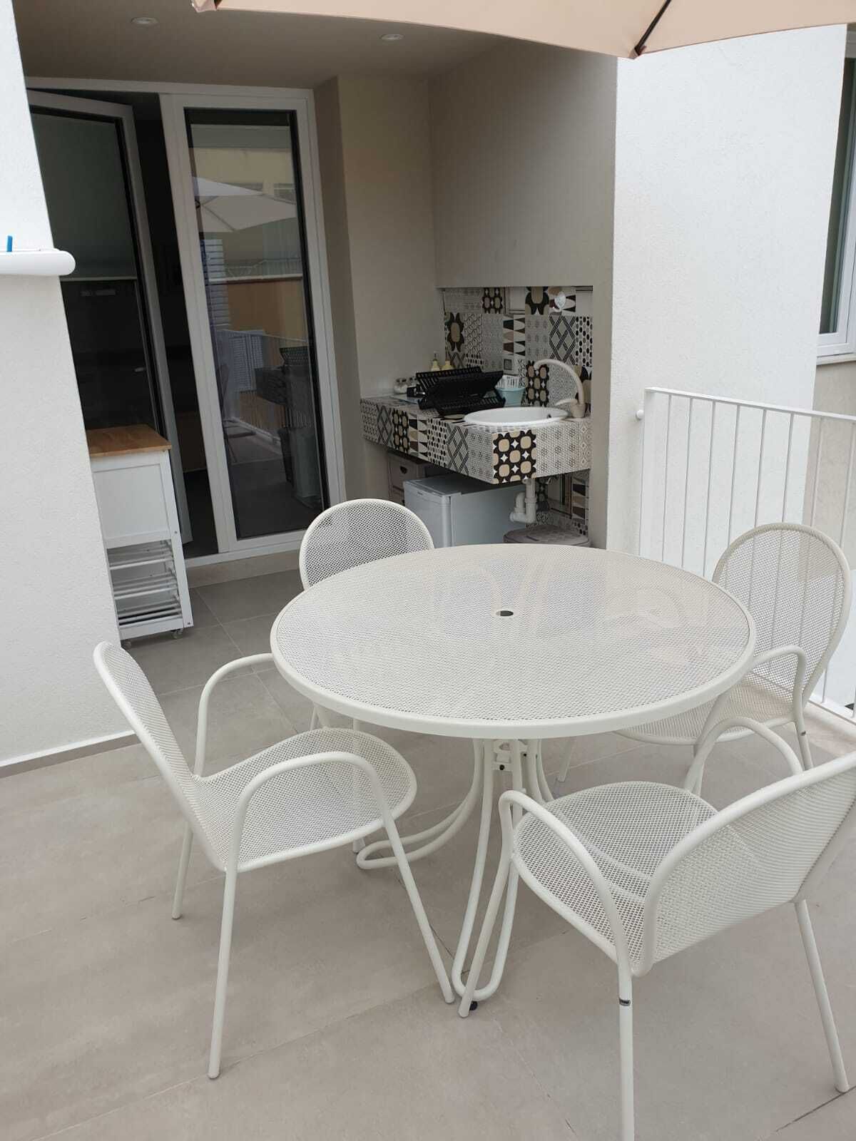 Un patio exterior blanco con una mesa redonda y cuatro sillas.
