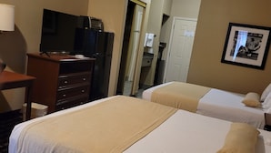 A hotel room with two beds, a desk with a television, a refrigerator, and a framed picture on the wall. - Cotulla Whitten Inn (Cotulla)