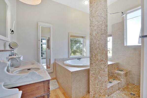 A modern bathroom with a marble sink, a freestanding bathtub, and a mosaic shower area.