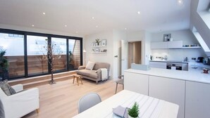 Un espacio habitable y de comedor moderno y de concepto abierto, con un gran ventanal, un sofá, una mesa de comedor y una zona de cocina.