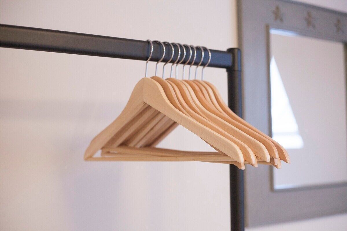 Un perchero de madera con múltiples perchas apoyado en una pared.