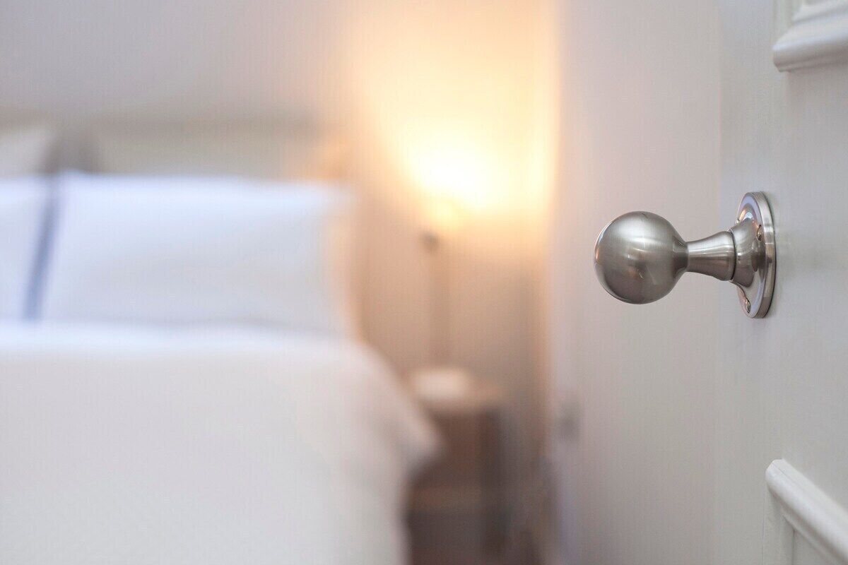 Una puerta con un pomo metálico redondo, un marco blanco y una fuente de luz al fondo.