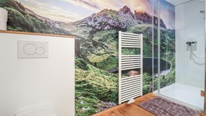 Een badkamer met een groot, sfeervol muurschildering, een douchecabine van glas en een witte radiator.