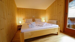 Een slaapkamer met houten lambrisering, een bed, twee nachtkastjes en een raam.