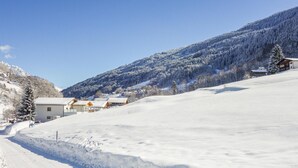 Een besneeuwd landschap met een skigebied, inclusief gebouwen met schuine daken, waarschijnlijk voor sneeuwactiviteiten.