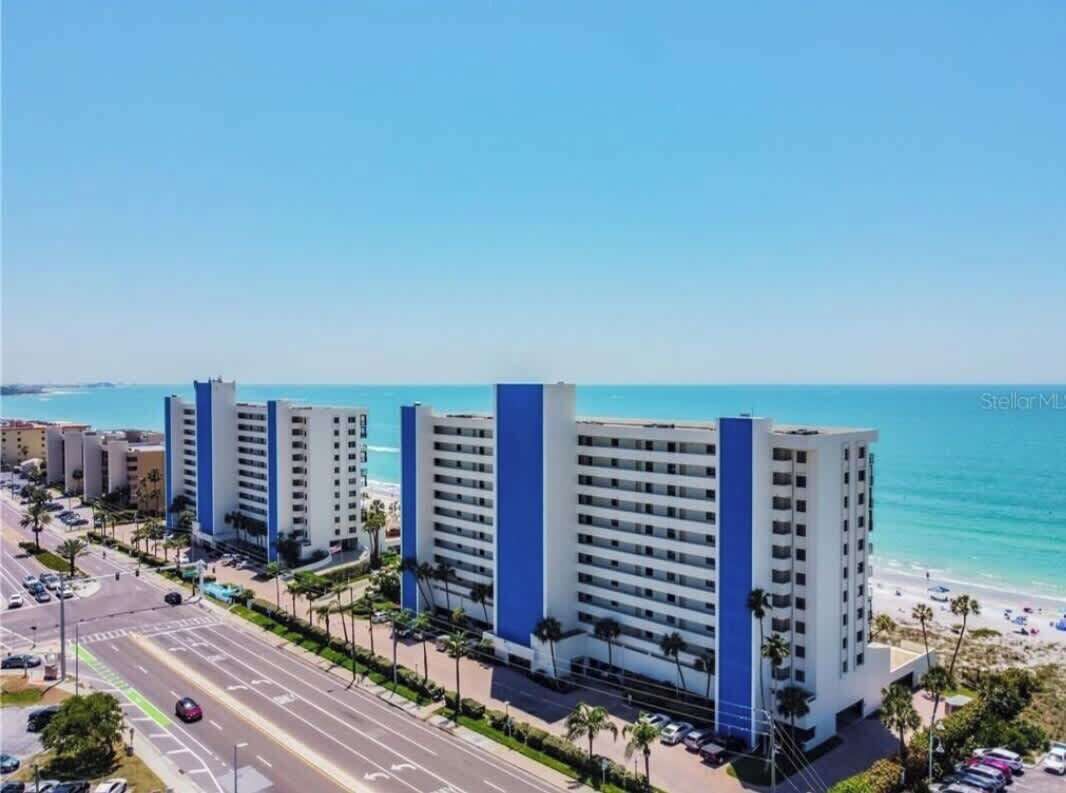 Een kusthotel met meerdere hoge gebouwen, een strand en een weg met voertuigen.