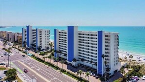 Een kusthotel met meerdere hoge gebouwen, een strand en een weg met voertuigen.