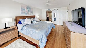 Een slaapkamer met een bed, nachtkastjes, een televisie en een deur naar een badkamer.