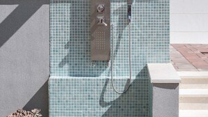 A modern outdoor shower with a tiled wall and a metal control panel. - Apartment house Ivan John (Podstrana)
