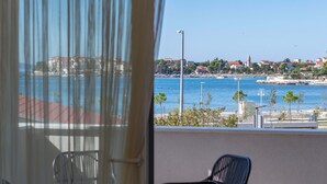 A balcony with a view of a coastal town, featuring a clear blue sea, a few boats, and buildings with red roofs. - Apartment house Ivan John (Podstrana)