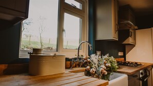 Eine Küche mit Holzarbeitsplatten, einem Spülbecken und einem Fenster mit Blick ins Freie.