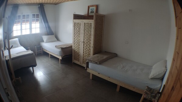 A dormitory room with two single beds, a wooden wardrobe, and a desk. - BigBlue Hostel Surf & Coworking (Taghazout)