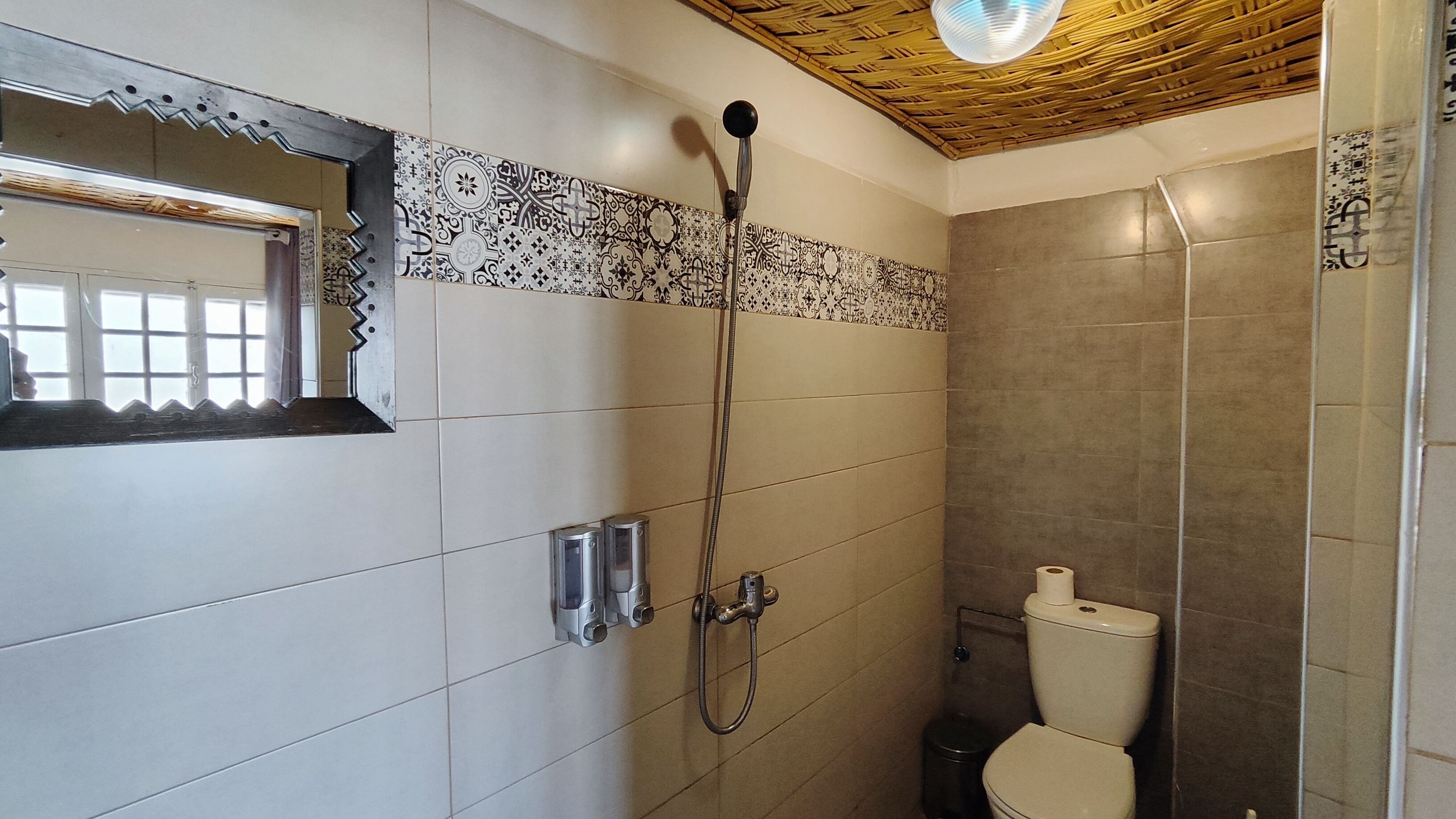 Une salle de bain avec une douche, des toilettes et un miroir.