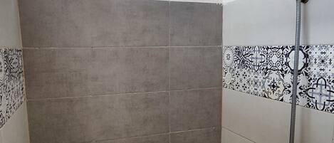 A shower with a bamboo ceiling, grey tiles, and patterned tiles on the walls.