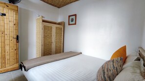 A bedroom with a bed, a wooden wardrobe, and a small framed picture on the wall. - BigBlue Hostel Surf & Coworking (Taghazout)