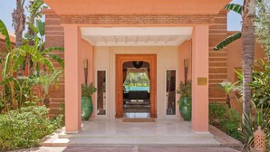 A building entrance with a covered porch, brick walls, and potted plants. - NEYLLA (Marrakech)