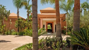 A hotel with a central entrance, palm trees, and a clear sky. - NEYLLA (Marrakech)