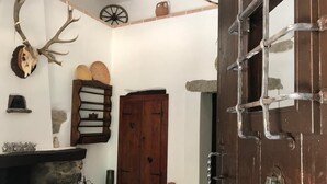 A rustic interior with a stone fireplace, wooden door, and antler display. - Cottage in Sardegna Barbagia (Fonni)