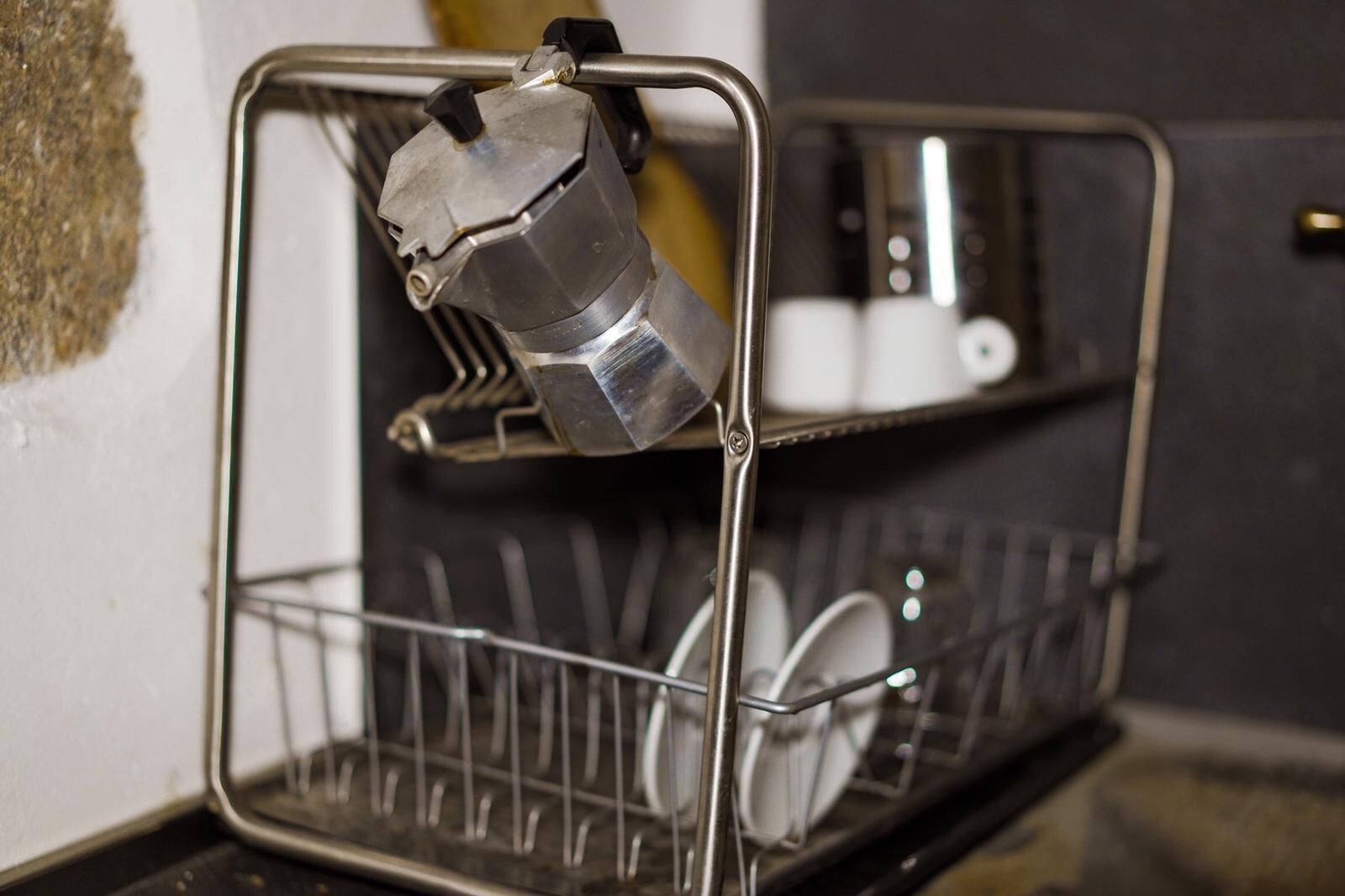 A metal rack with a coffee maker and a dish rack.