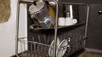 A metal rack with a coffee maker and a dish rack.