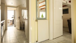 Un couloir avec une porte blanche, un radiateur et un miroir accroché au mur.