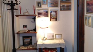 Une pièce comprenant une table, une chaise, un radiateur et divers tableaux encadrés accrochés au mur.