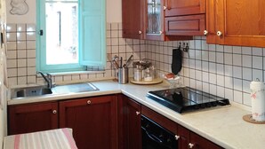 Une cuisine avec des meubles de rangement en bois, un poêle noir, un évier et une fenêtre donnant sur l’extérieur.