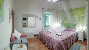 Une chambre à coucher avec un lit, une table de chevet et une petite table sur laquelle se trouvent une bouteille et des verres.