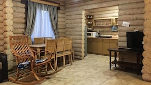 A log cabin interior with a dining area, kitchen, and a television. - Eco-resort Izki (Izky)