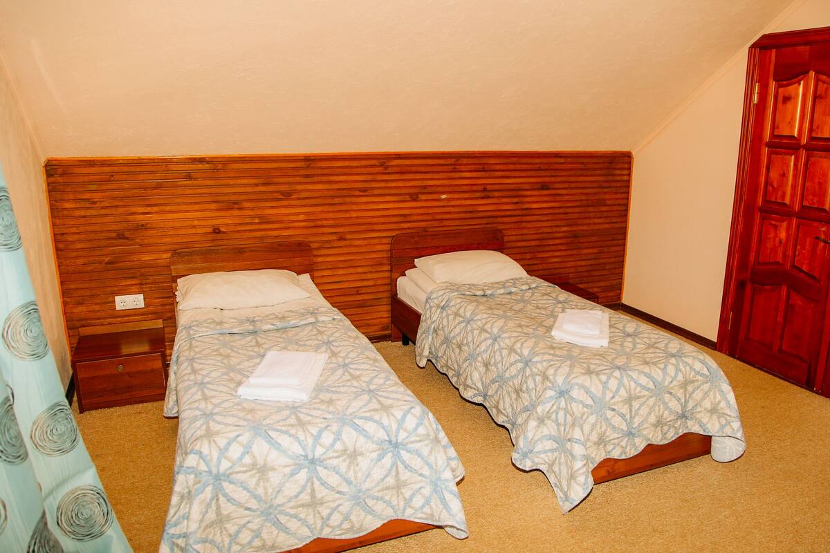 A bedroom with two single beds, wooden headboard, and a red door.