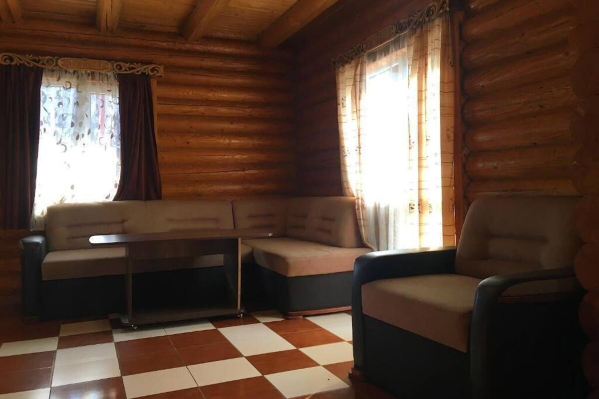 A log cabin interior with a checkered floor, a sofa, a chair, and a small table.