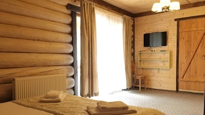 A log cabin room with a bed, a chair, a television, and a wooden door. - Eco-resort Izki (Izky)
