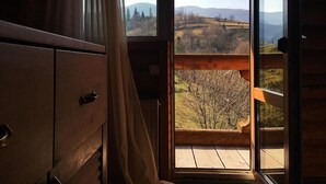 A wooden interior with a large window offering a view of a hilly landscape. - Eco-resort Izki (Izky)