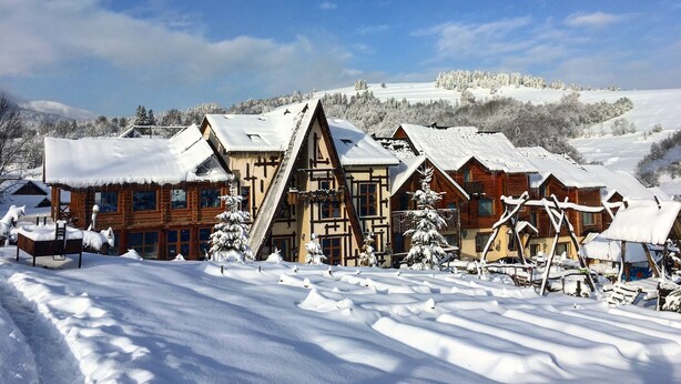 A snow-covered lodge with traditional architecture, including wooden cabins and a prominent triangular structure. - Eco-resort Izki (Izky)