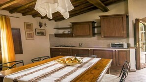 A rustic kitchen with wooden cabinets, a stove, and a dining table set with bread.