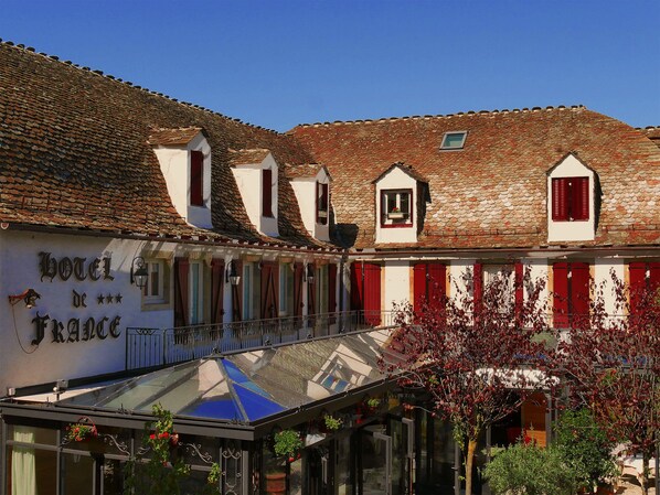 A building with a sign reading "Hotel de France" and a glass-roofed structure in front. - Hôtel de France (Mende)