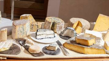 A variety of cheeses displayed on a wooden board with a knife.