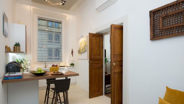 Una cocina compacta con comedor, una puerta de madera y un cojín amarillo.