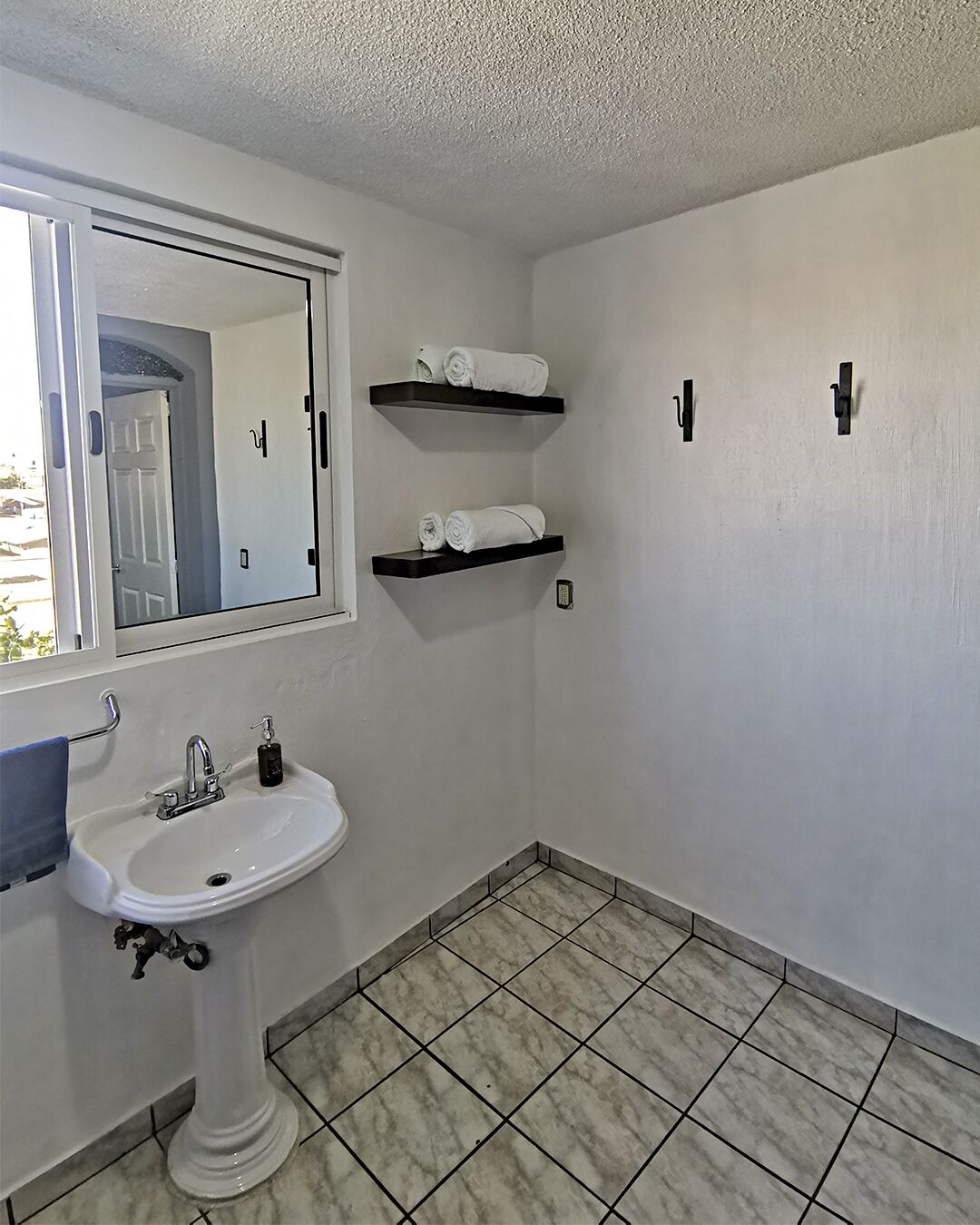 A bathroom with a pedestal sink, two towel racks, and a mirror.