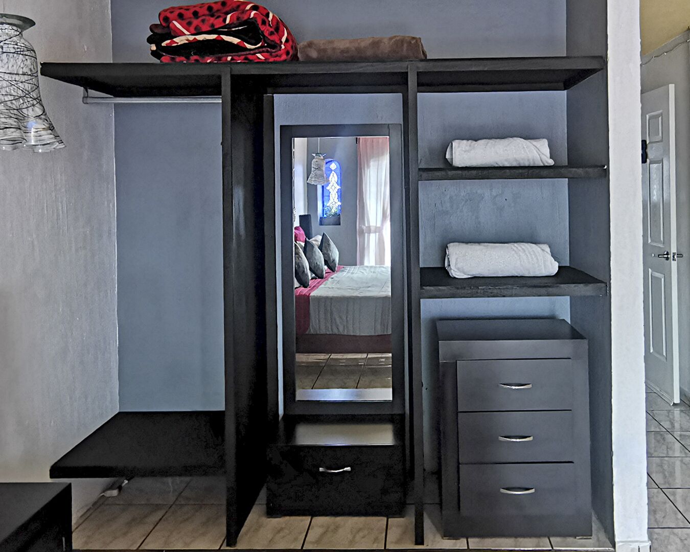 A modern bedroom with a built-in wardrobe, a bed with pillows, and a hanging light fixture.