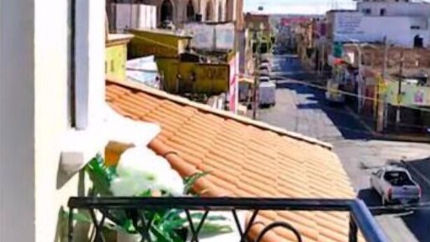 A balcony with a view of a historic church and a street below.
