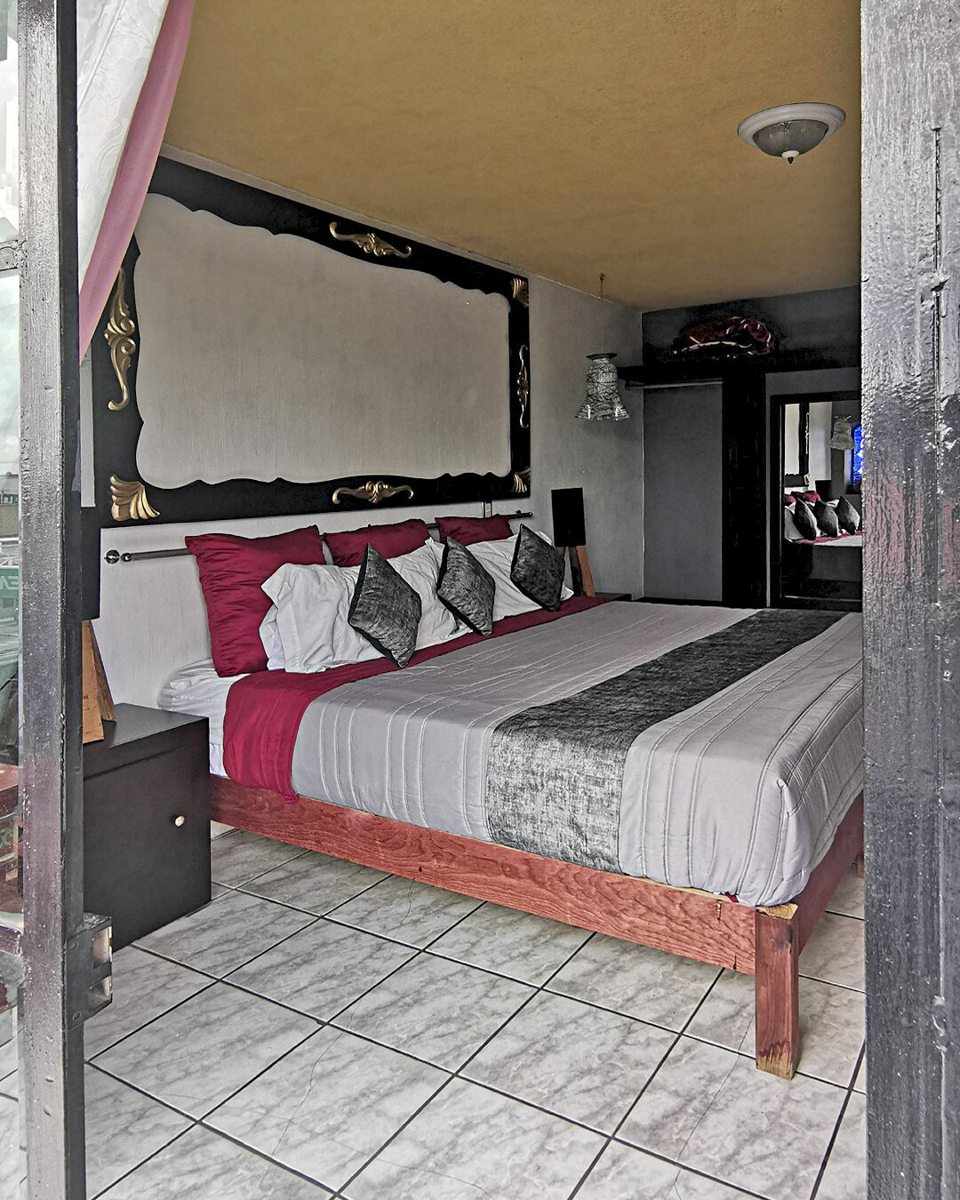 Un dormitorio con cama, cabecera, mesita de noche y mesita auxiliar.